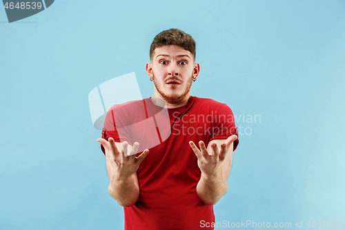 Image of The young attractive man looking suprised isolated on blue