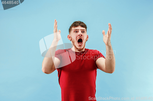 Image of The young attractive man looking suprised isolated on blue