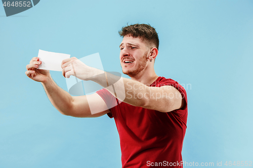 Image of Young boy with a surprised expression bet slip on blue background