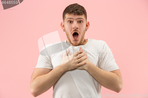 Image of The young attractive man looking suprised isolated on pink