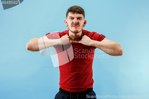 Image of The young emotional angry man screaming on blue studio background