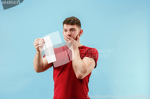 Image of Young boy with a surprised expression bet slip on blue background