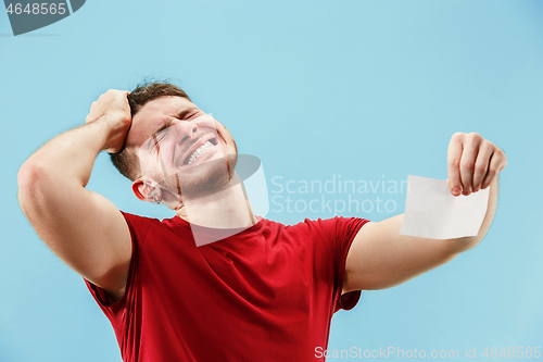 Image of Young boy with a surprised expression bet slip on blue background