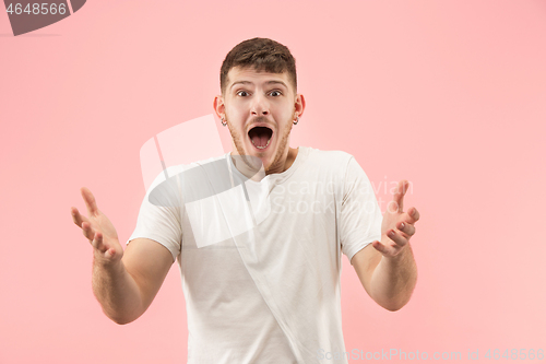 Image of The young attractive man looking suprised isolated on pink