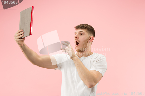 Image of portrait of smiling man pointing at laptop with blank screen isolated on white