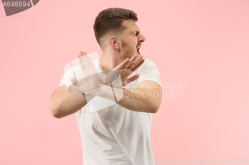 Image of Beautiful male half-length portrait isolated on pink studio backgroud. The young emotional surprised man