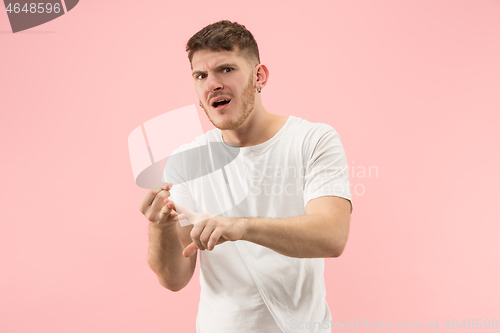 Image of Beautiful male half-length portrait isolated on pink studio backgroud. The young emotional surprised man