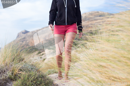 Image of Relaxed woman in pink shorts and black hoodie enjoying beautiful nature at serene landscape at Balos beach, Greece. Concept of vacations, freedom, happiness, joy and well being