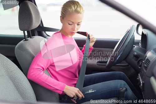 Image of Beautiful woman fastening seat belt.