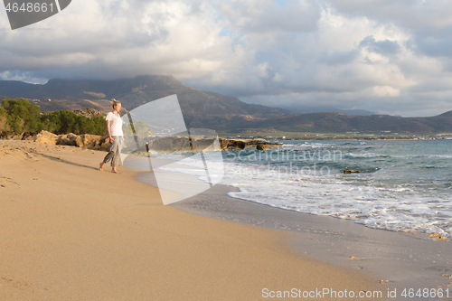 Image of Woman walking on sand beach at golden hour