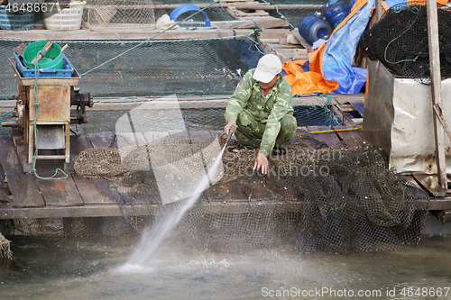 Image of VIETNAM, HA LONG BAY - JANUARY 03, 2015 - Fisherman washing his net
