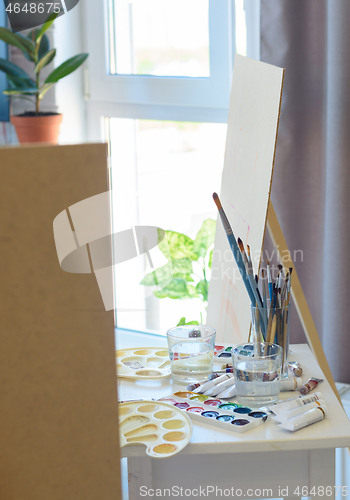 Image of artist\'s workplace with easel, brushes and paints