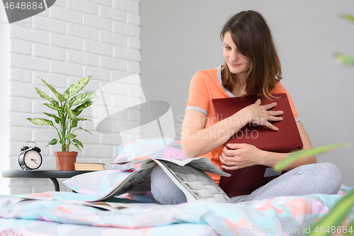 Image of Girl sitting on the bed and reading a newspaper with job advertisements