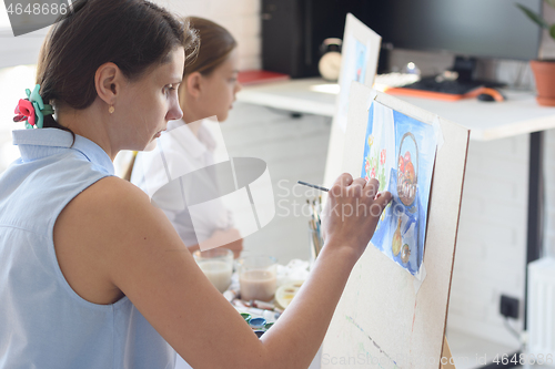 Image of Girl sits next to the child and paints still life