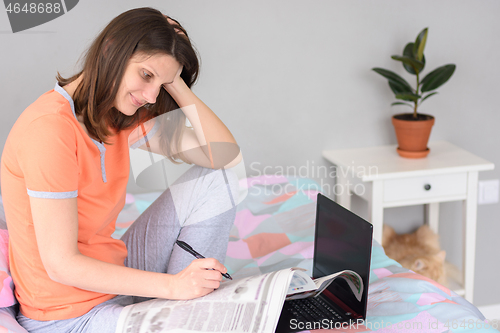 Image of Girl browsing a newspaper at home and looking for job ads
