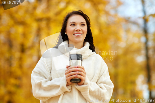 Image of woman with hot drink in tumbler at autumn park