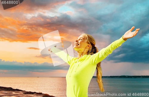 Image of happy woman in sports clothes at seaside