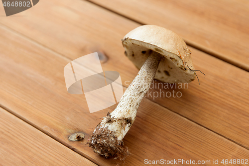 Image of brown cap boletus mushroom on wooden background