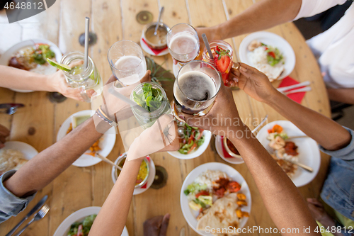 Image of friends eating and clinking glasses at restaurant