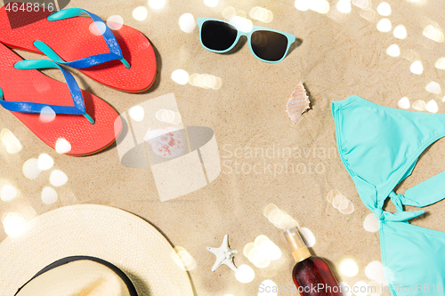 Image of straw hat, flip flops and sunglasses on beach sand