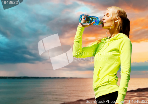 Image of woman drinking water after exercising at seaside