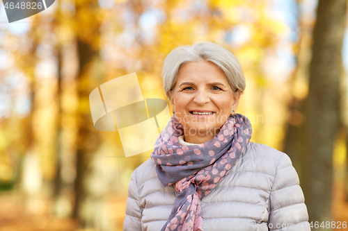 Image of portrait of happy senior woman at autumn park