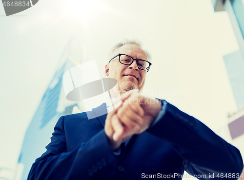 Image of senior businessman checking time on his wristwatch