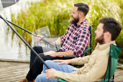 Image of friends with fishing rods at lake or river