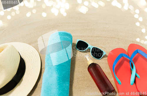 Image of straw hat, flip flops and sunglasses on beach sand