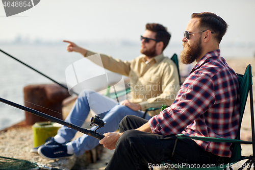 Image of happy friends with fishing rods on pier