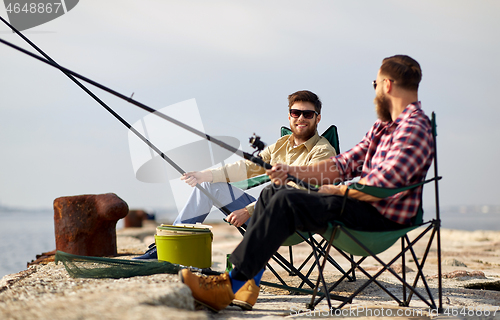 Image of happy friends with fishing rods on pier