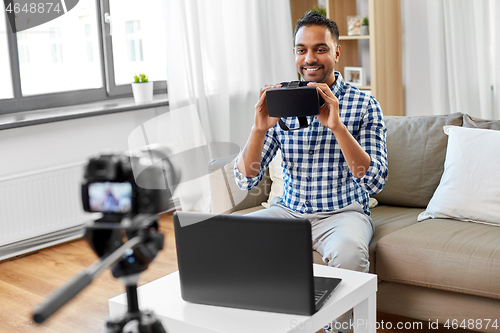 Image of male blogger with vr glasses videoblogging at home