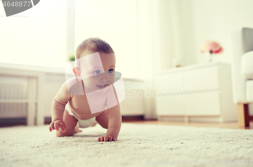 Image of little baby in diaper crawling on floor at home