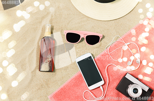 Image of smartphone, camera, towel, hat and shades on beach