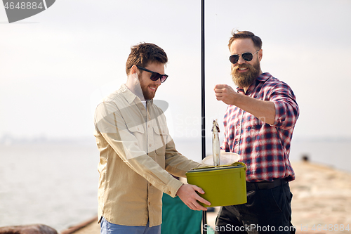 Image of friends with fish, bucket and fishing rod on pier