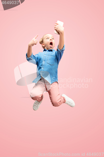 Image of Young happy caucasian teen girl jumping with phone in the air, isolated on pink studio background.