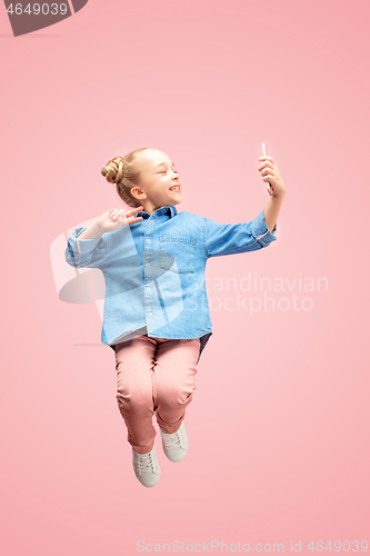 Image of Young happy caucasian teen girl jumping with phone in the air, isolated on pink studio background.