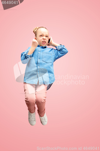 Image of Young happy caucasian teen girl jumping with phone in the air, isolated on pink studio background.