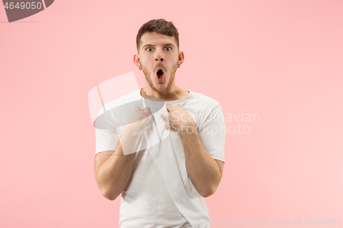 Image of Beautiful male half-length portrait isolated on pink studio backgroud. The young emotional surprised man