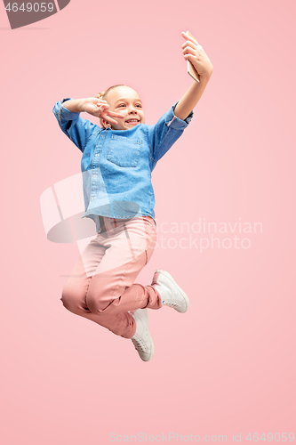 Image of Young happy caucasian teen girl jumping with phone in the air, isolated on pink studio background.