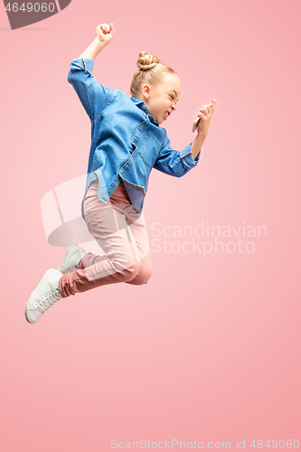 Image of Young happy caucasian teen girl jumping with phone in the air, isolated on pink studio background.