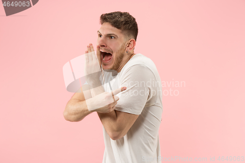 Image of The young man whispering a secret behind her hand over pink background