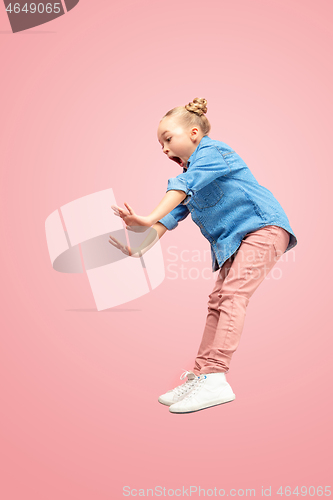 Image of Young scared caucasian teen girl jumping in the air, isolated on pink studio background.