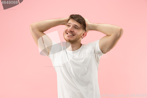 Image of The happy businessman standing and smiling against pink background.