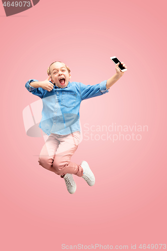 Image of Young happy caucasian teen girl jumping with phone in the air, isolated on pink studio background.