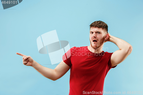 Image of Young man with disgusted expression repulsing something, isolated on the blue