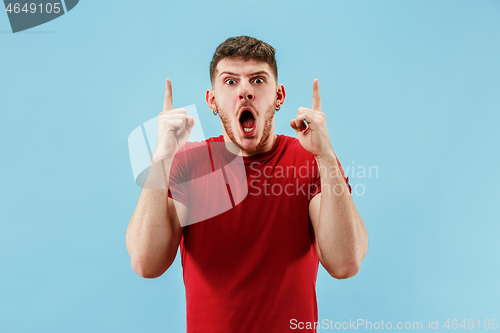 Image of The young attractive man looking suprised isolated on blue