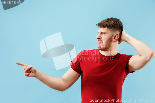 Image of Young man with disgusted expression repulsing something, isolated on the blue