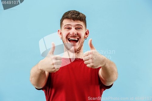 Image of The happy businessman standing and smiling against blue background.