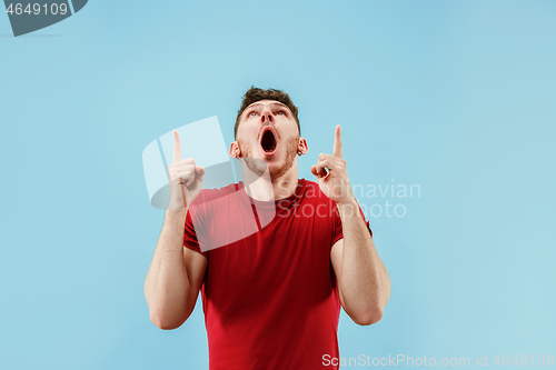 Image of The young attractive man looking suprised isolated on blue